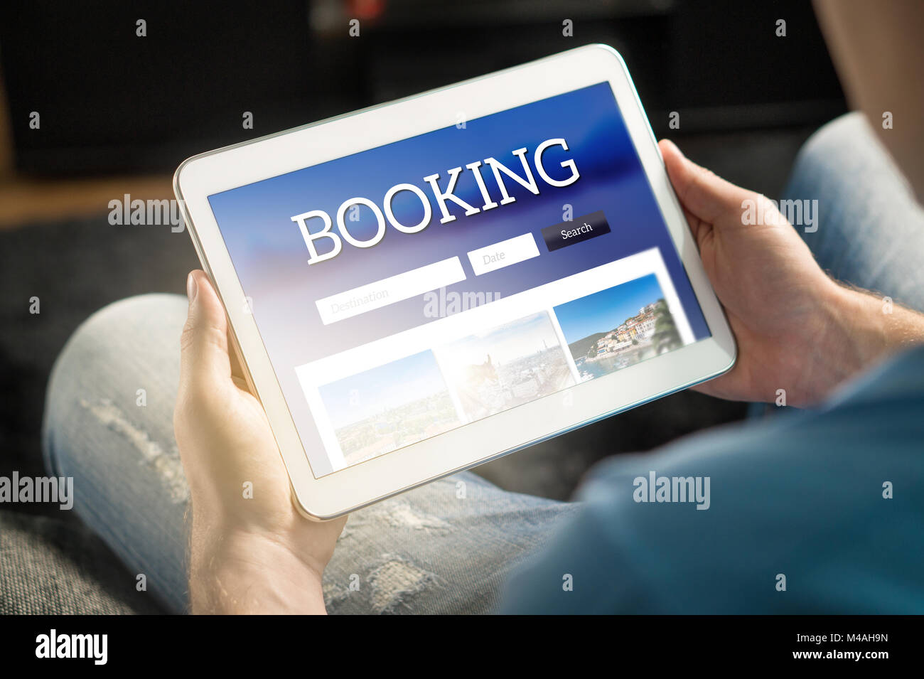 Booking app or website on tablet screen. Man searching hotel and flights for holiday and vacation with travel application. Person holding smart device Stock Photo