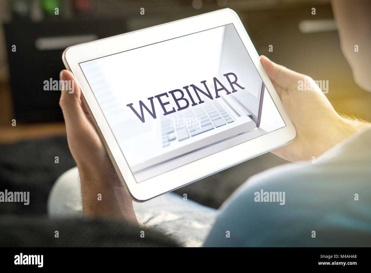 Webinar on tablet screen. Man holding smart mobile device and participating in a web seminar. Stock Photo