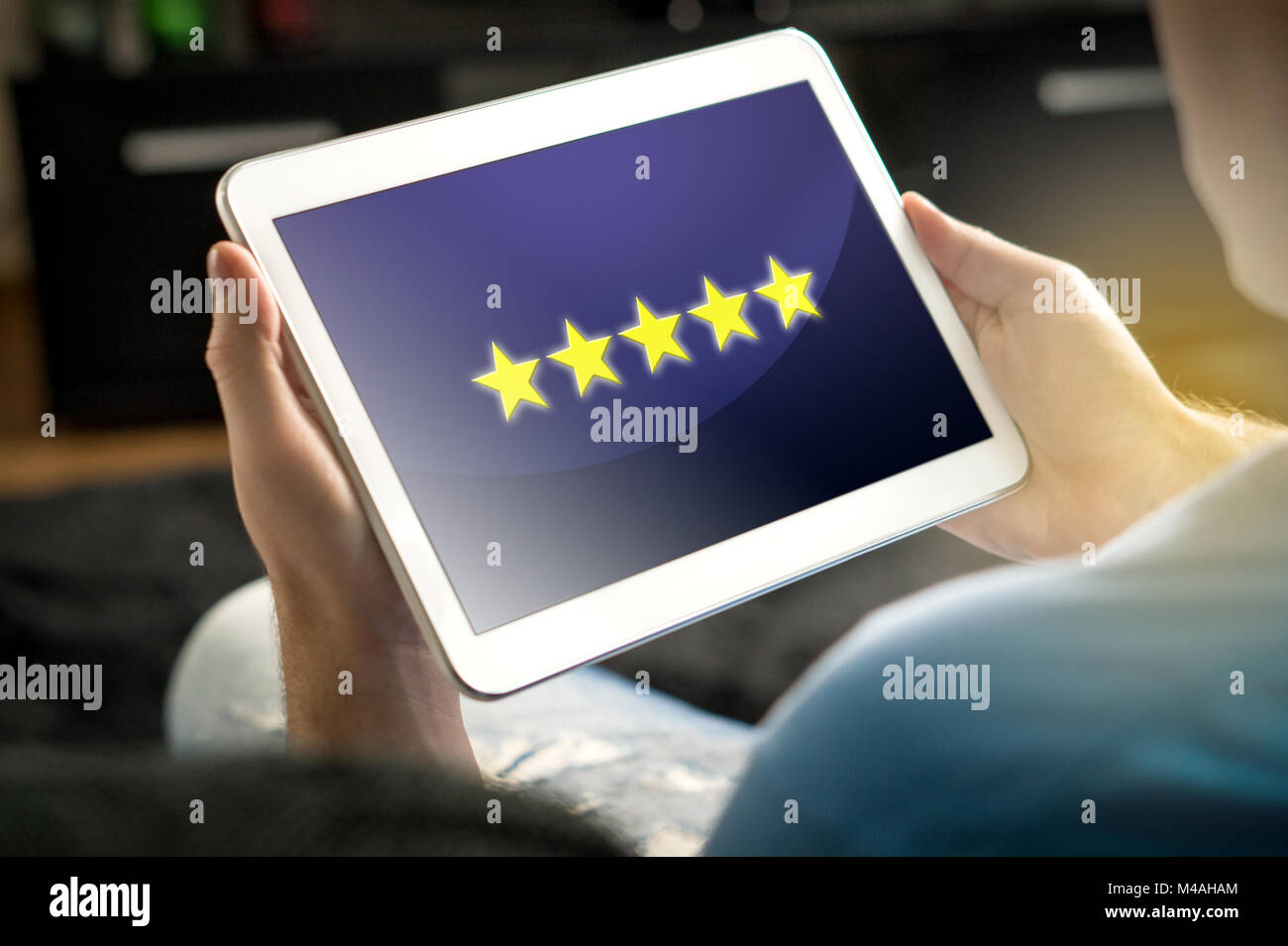 Five star rating and review from satisfied and happy customer and reviewer. Man holding tablet with an imaginary criticism application, social media. Stock Photo