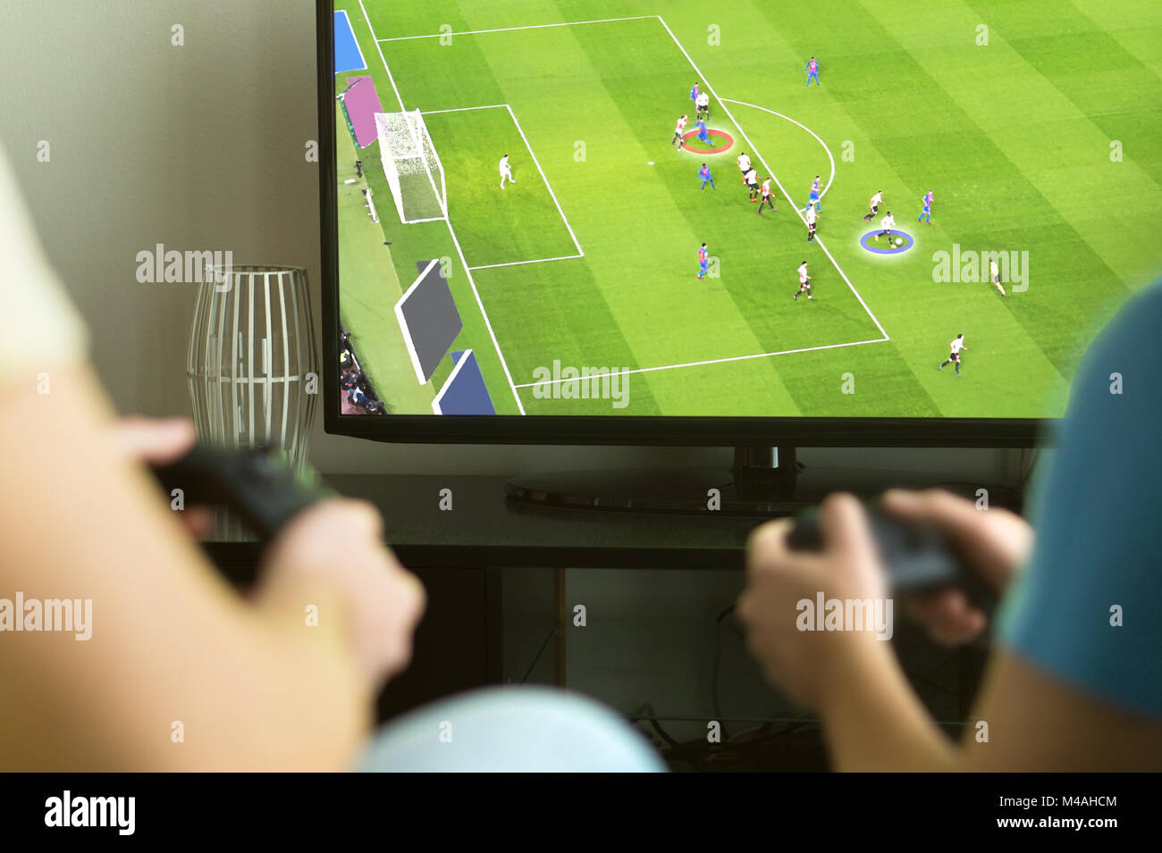 Two guys playing imaginary multiplayer soccer or football video game with console and tv. Guys night, party and weekend concept. Stock Photo