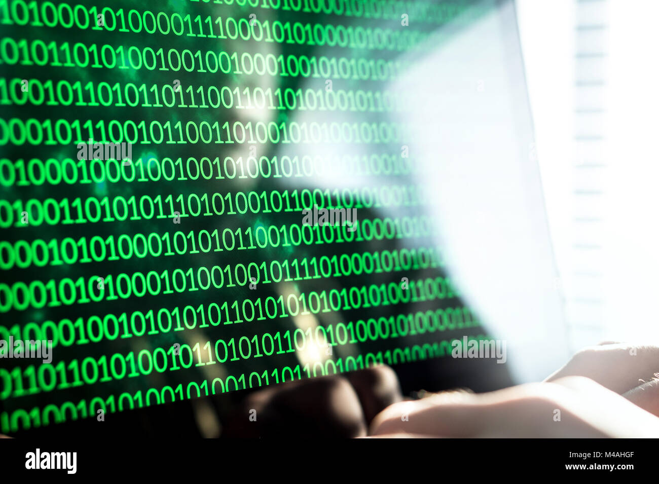 Hacker writing code with laptop computer. Binary numbers, zero and one on monitor screen. Cyber security threat, attack and online crime concept. Stock Photo