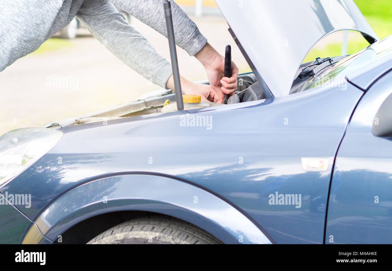 Man fixing engine under the hood with a monkey wrench. Car repair, maintenance and vehicle inspection concept. Stock Photo