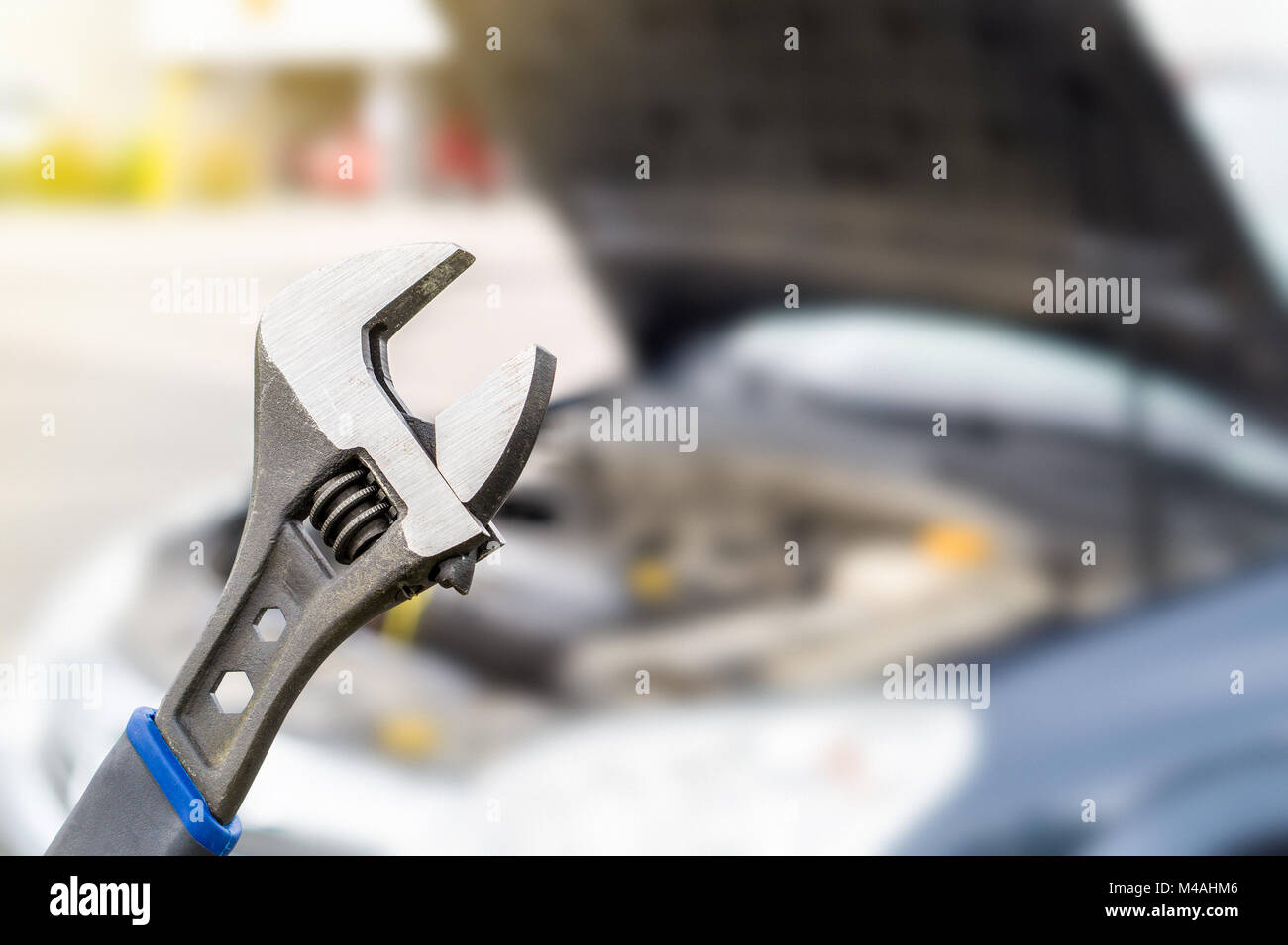 Car repair, maintenance and vehicle inspection concept. Wrench and a car with under the hood and engine view. Selective focus to fixing tool. Stock Photo