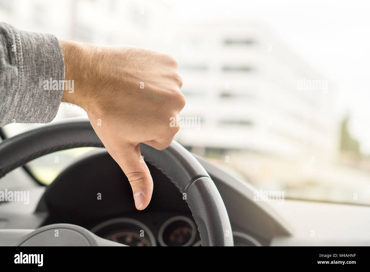 Sad driver showing thumbs up in car. Dissatisfied man. Bad customer service by repair shop. Vehicle broken. Failed driving school test or inspection.  Stock Photo