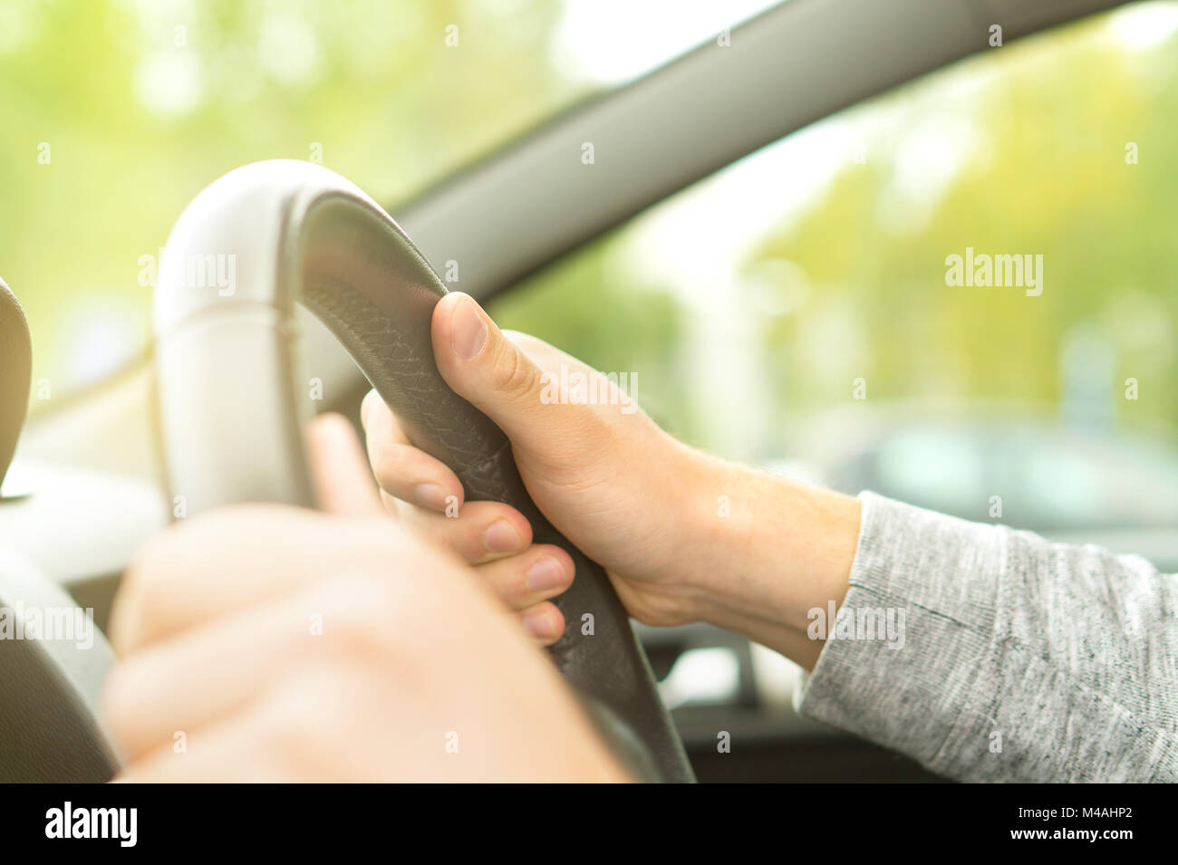 Happy man driving car in summer. Driver holding steering wheel with both hands. Road trip, travel or commute concept. Stock Photo