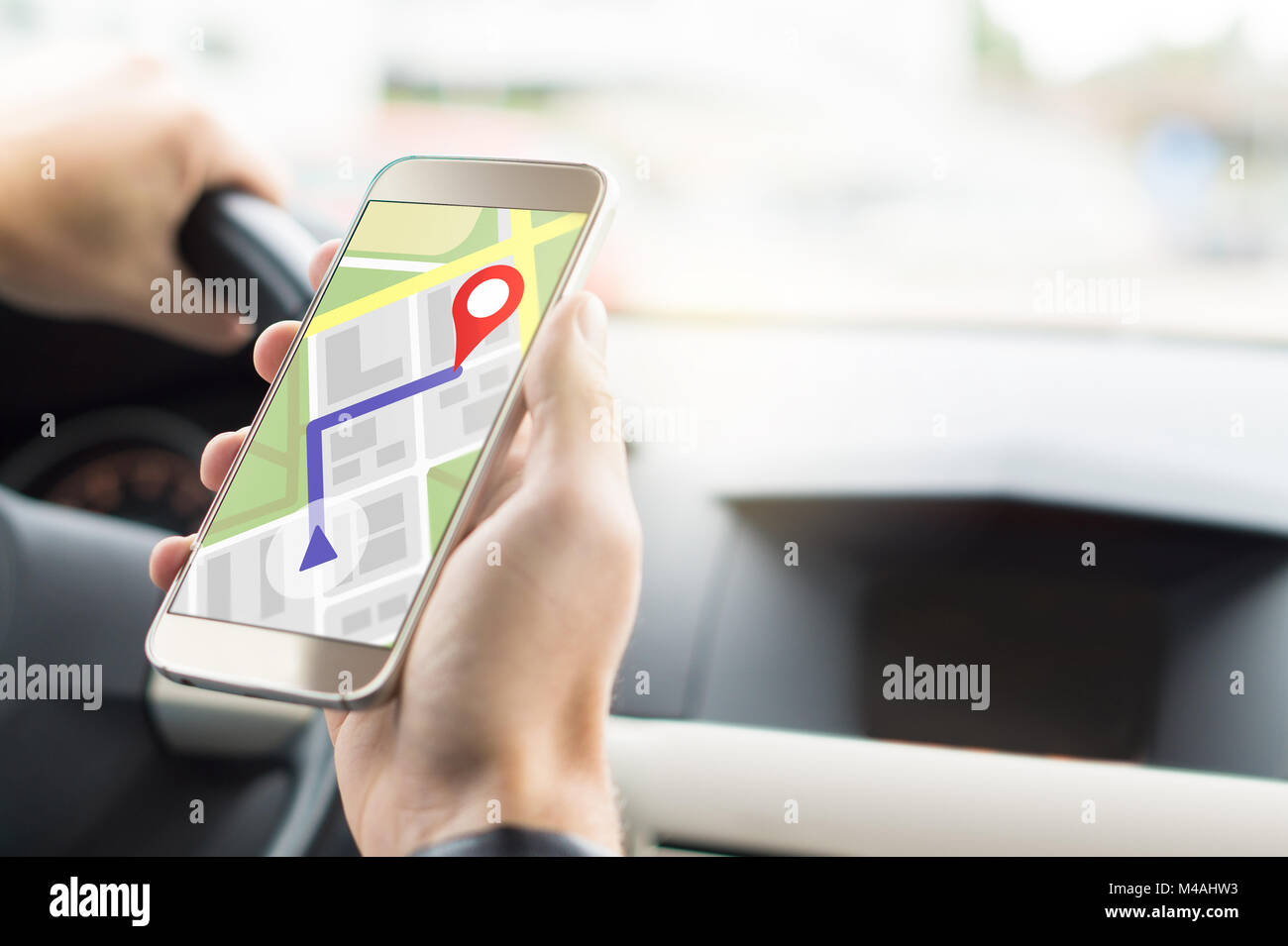 Navigation with mobile app in smartphone. Online map and GPS application on cellphone screen. Inside view in car to hand holding phone in cockpit. Stock Photo