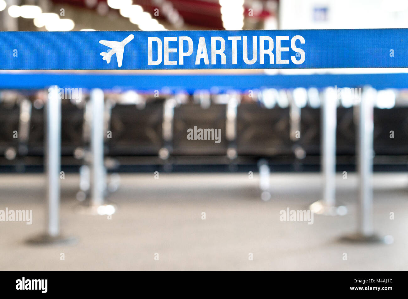 Departures text with airplane icon on a queue barrier. Waiting area and lounge seats at airport terminal. Travel, vacation and tourism concept. Stock Photo