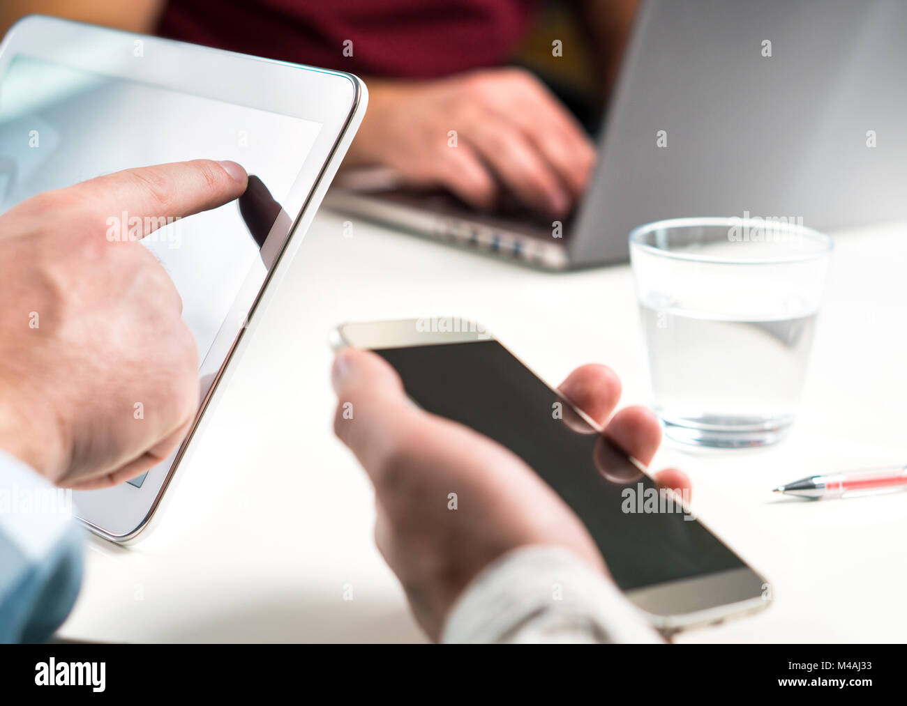 Casual business people having meeting. Three friends working together in office with modern mobile and smart devices. Sharing ideas, teamwork. Stock Photo