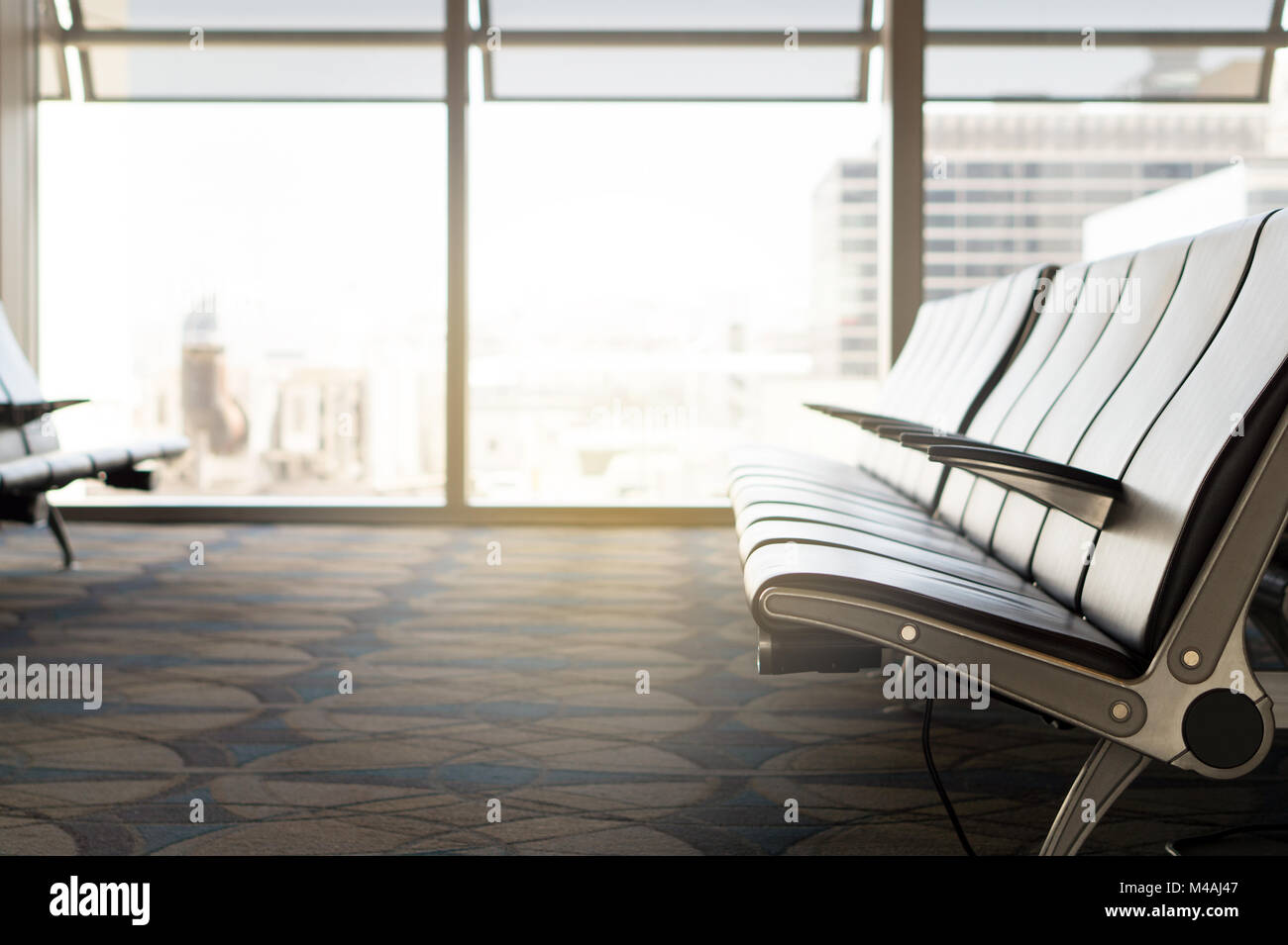 Waiting room at airport. Empty seats at gate in terminal. Light from window. Departure lounge. Stock Photo