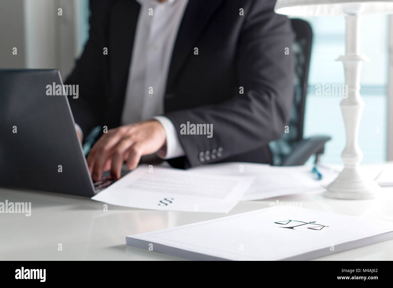 Scale and justice sign on pile of paper. Lawyer working in office. Attorney writing a legal document with laptop computer. Stock Photo