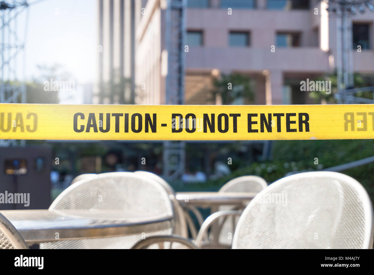 Caution, do not enter line tape and ribbon in city, outdoor terrace, restaurant or building. Construction or crime scene with a warning text. Forbidde Stock Photo