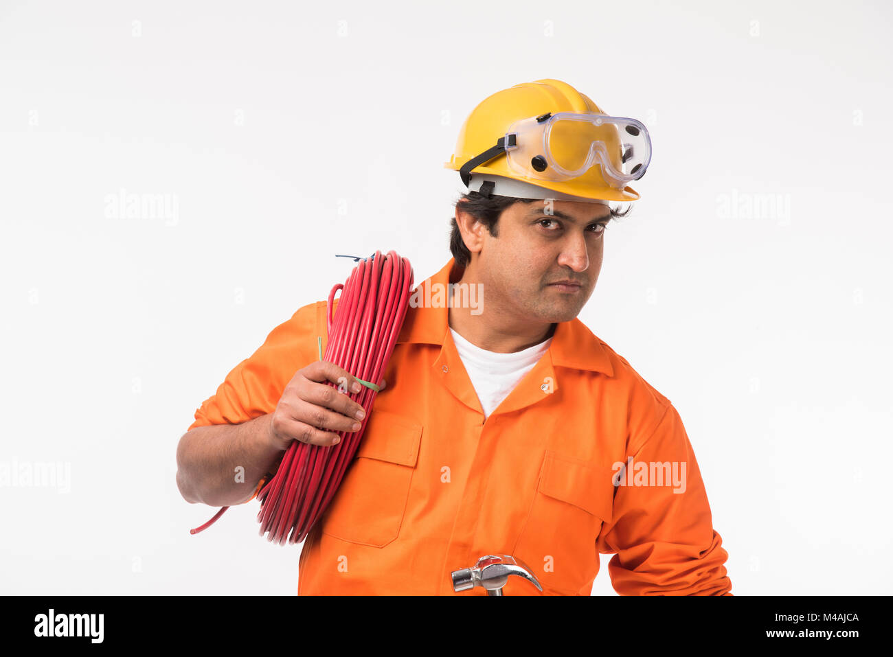 Indian electrician engineer in action with wire cutter, drilling machine etc, standing isolated