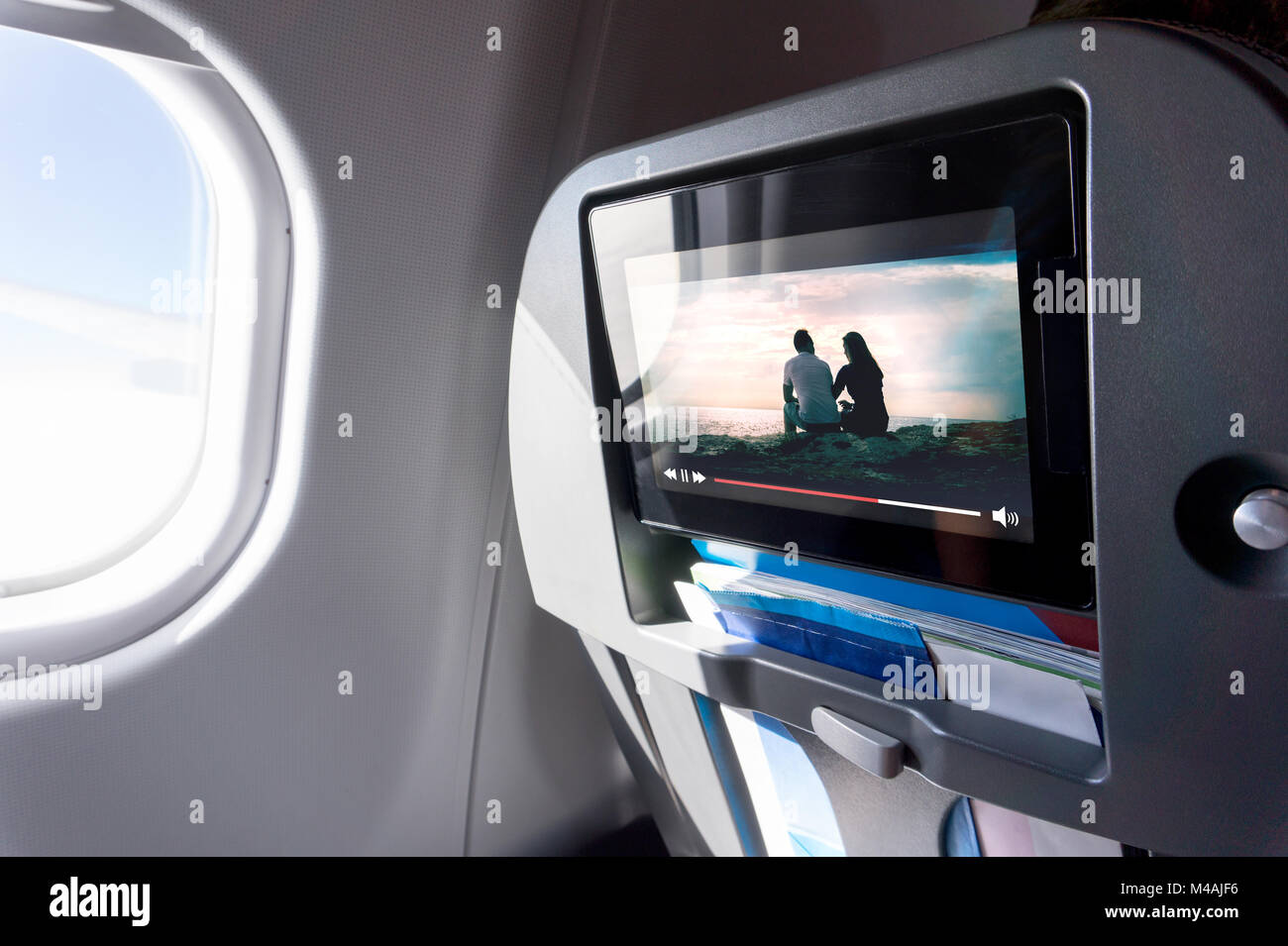 Watching movie on an airplane touch screen. Imaginary film playing on a video player in monitor during long flight. Entertainment service system. Stock Photo