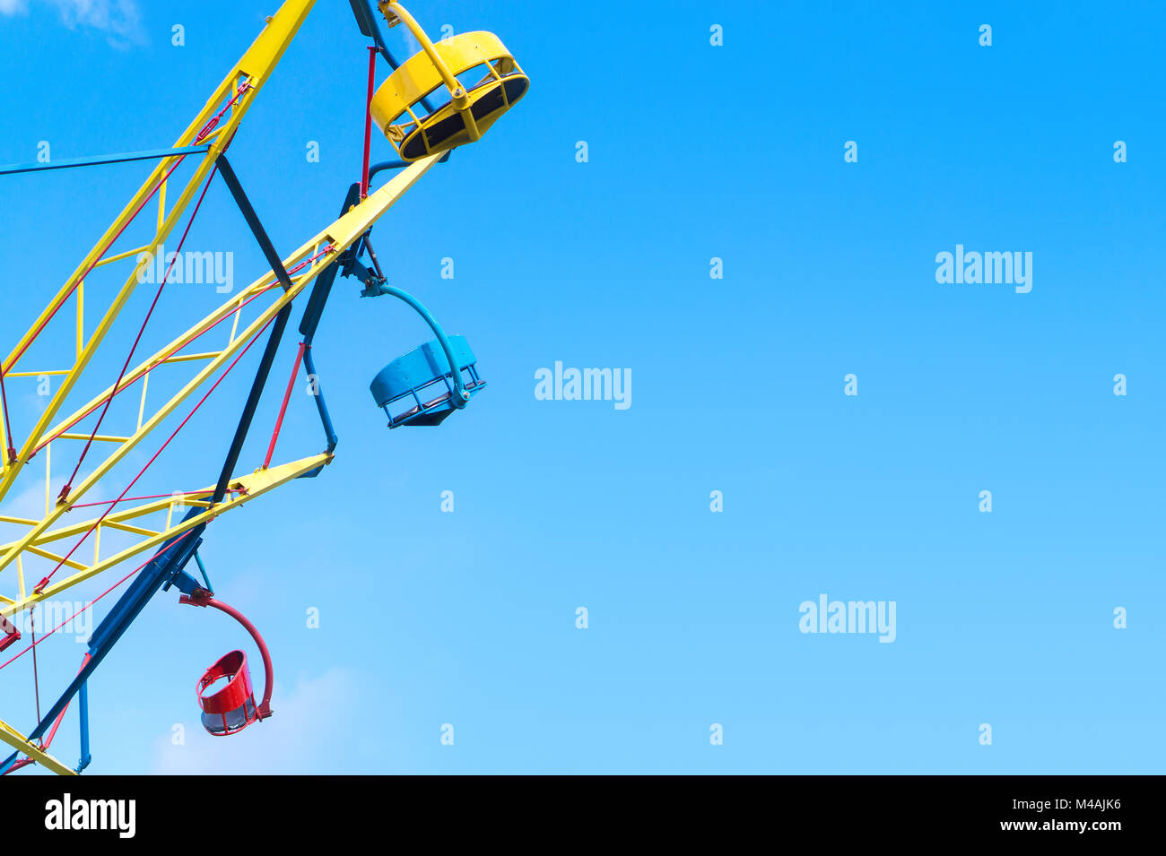 Amusement park background template with negative copy space. Colorful theme park ride against clear blue sky in summer. Stock Photo