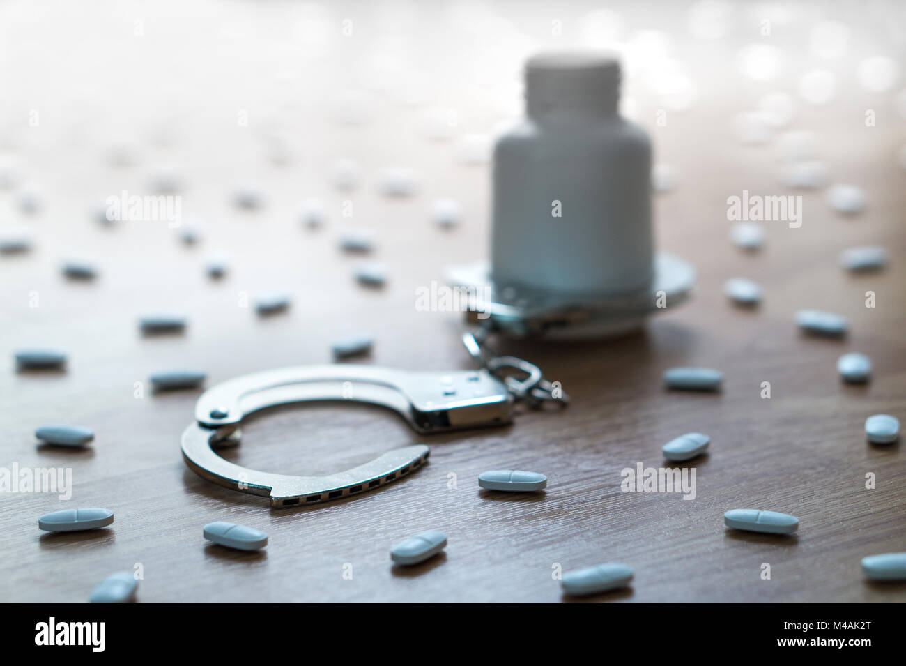 Drug addiction, medical abuse and narcotics hook and dependence concept. Medicine bottle handcuffed and surrounded by many pills. Tablet overdose. Stock Photo