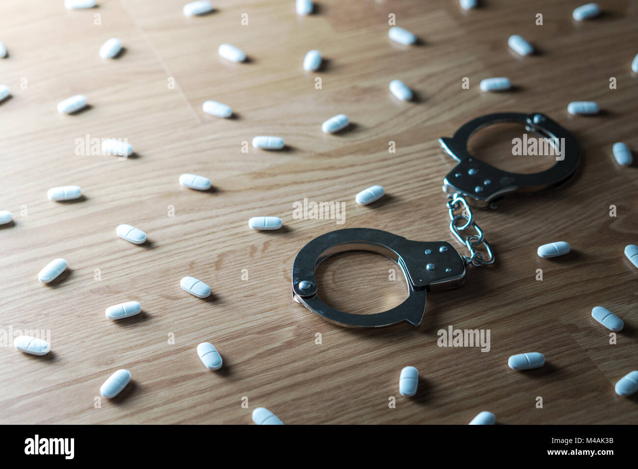 Drug addiction, medical abuse and narcotics hook and dependence concept. Handcuffs surrounded by many pills. Tablet overdose. Withdrawal symptoms Stock Photo