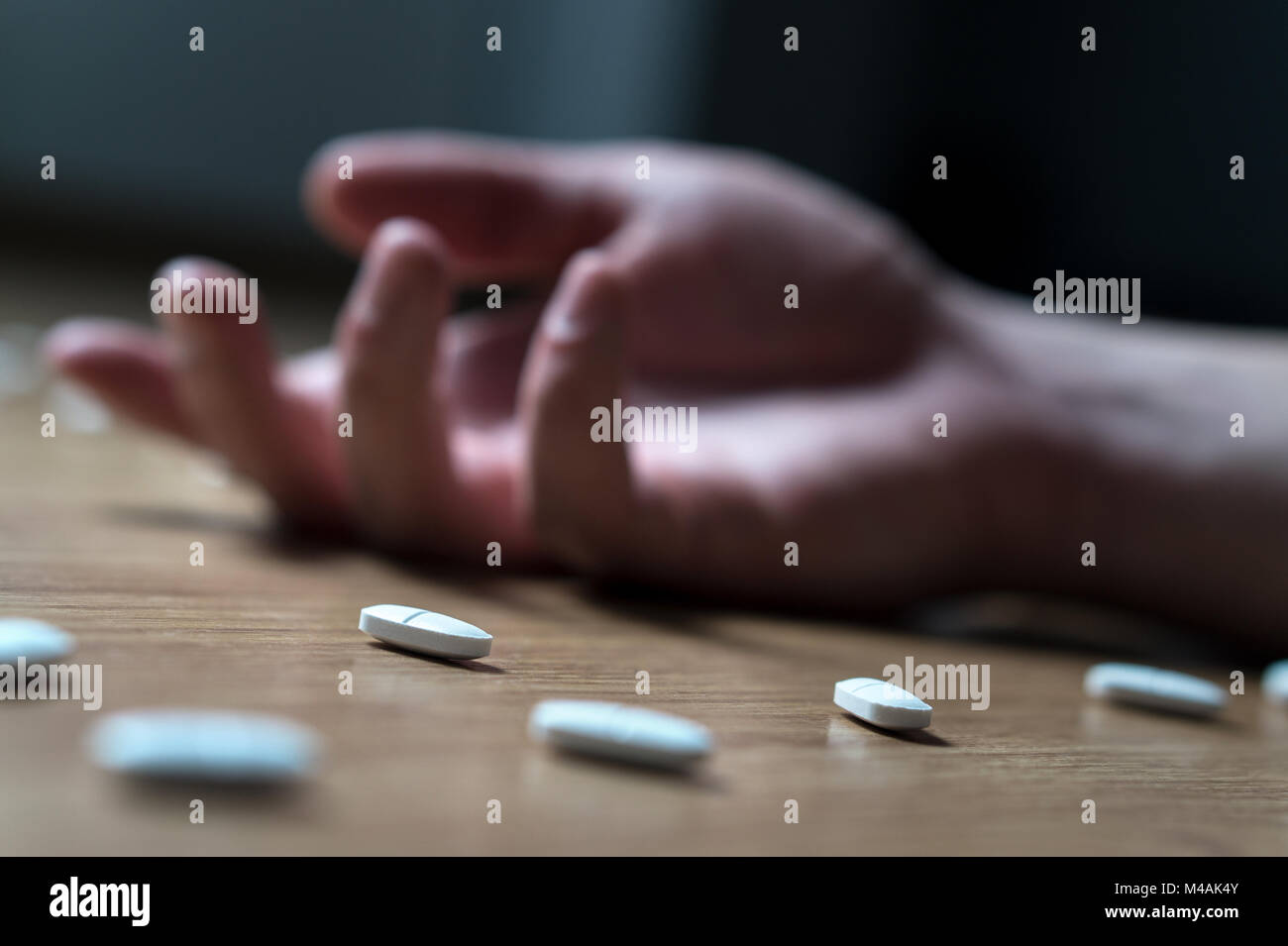 Drug addiction, medical abuse and narcotics hook and dependence concept. Drug addict with withdrawal symptoms lying on floor. Tablet overdose. Suicide Stock Photo