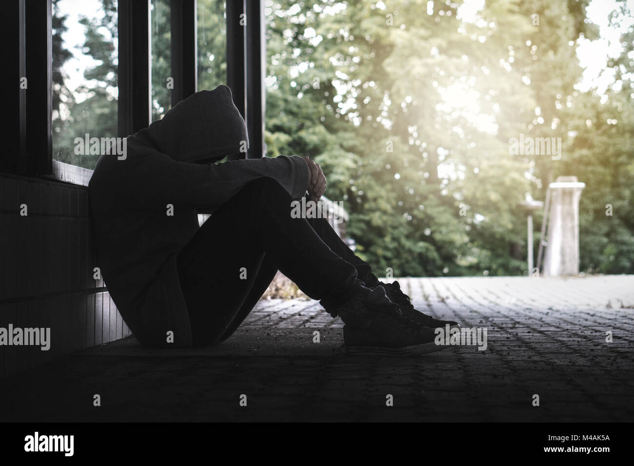 Depression, social isolation, loneliness, mental health and discrimination concept. Sad, lonely, depressed and unhappy man. Hooded person sitting. Stock Photo