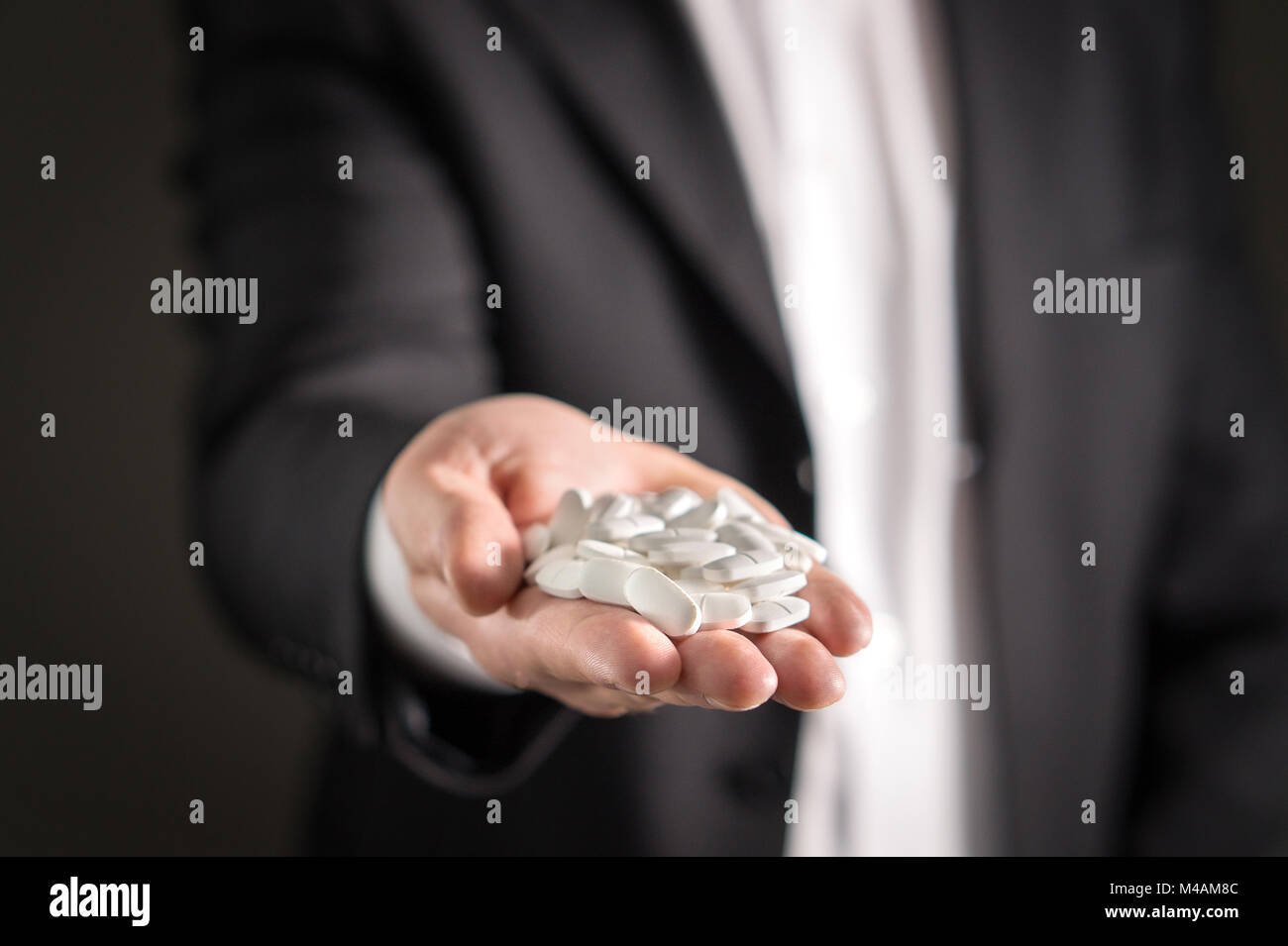 Pharmaceutical representative, consultant or head director or manager of medicine company with white medicine and pills. Man in a suit holding tablets Stock Photo