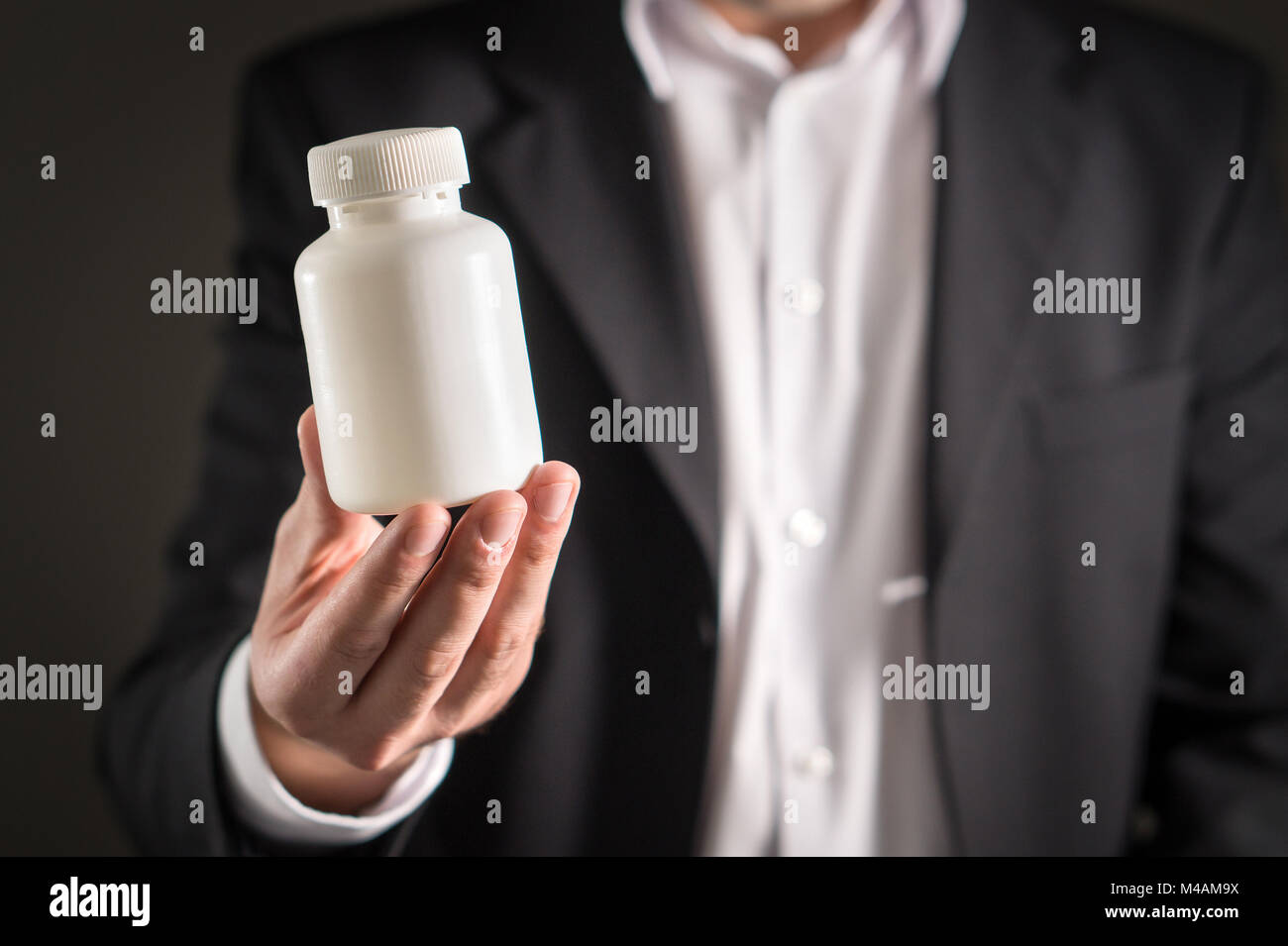 Pharmaceutical representative, consultant or head director or manager of medicine company with medicine bottle. Man in a suit holding pills or tablets Stock Photo