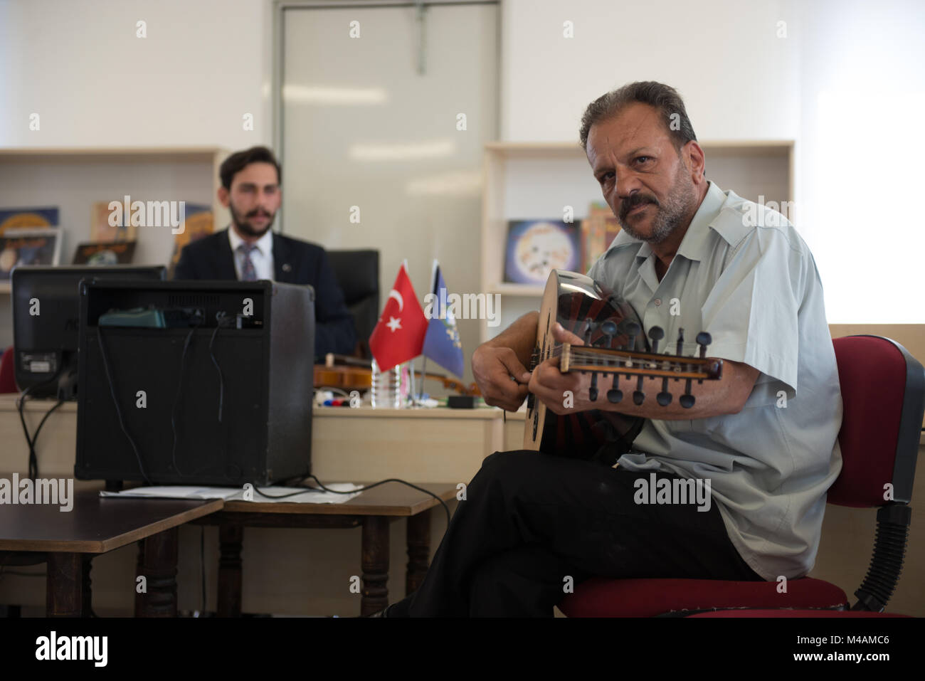 A Syrian refugee plays a stringed instrument during a demonstration at the music workshop in the refugee camp of Kilis, Turkey, near the Syrian border. Stock Photo