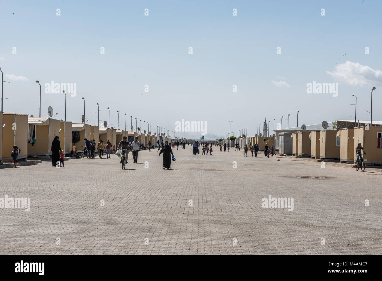 A group of refugees is walking along the main street of the Kilis refugee camp in Turkey, near the border with Syria. Stock Photo