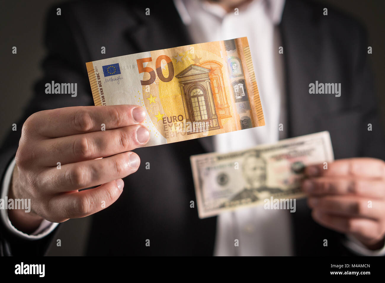 Dollar vs euro. Business man in suit holding 50 banknote and bill in both currency in hand. Exchange rate, world economy and financial concept. Stock Photo