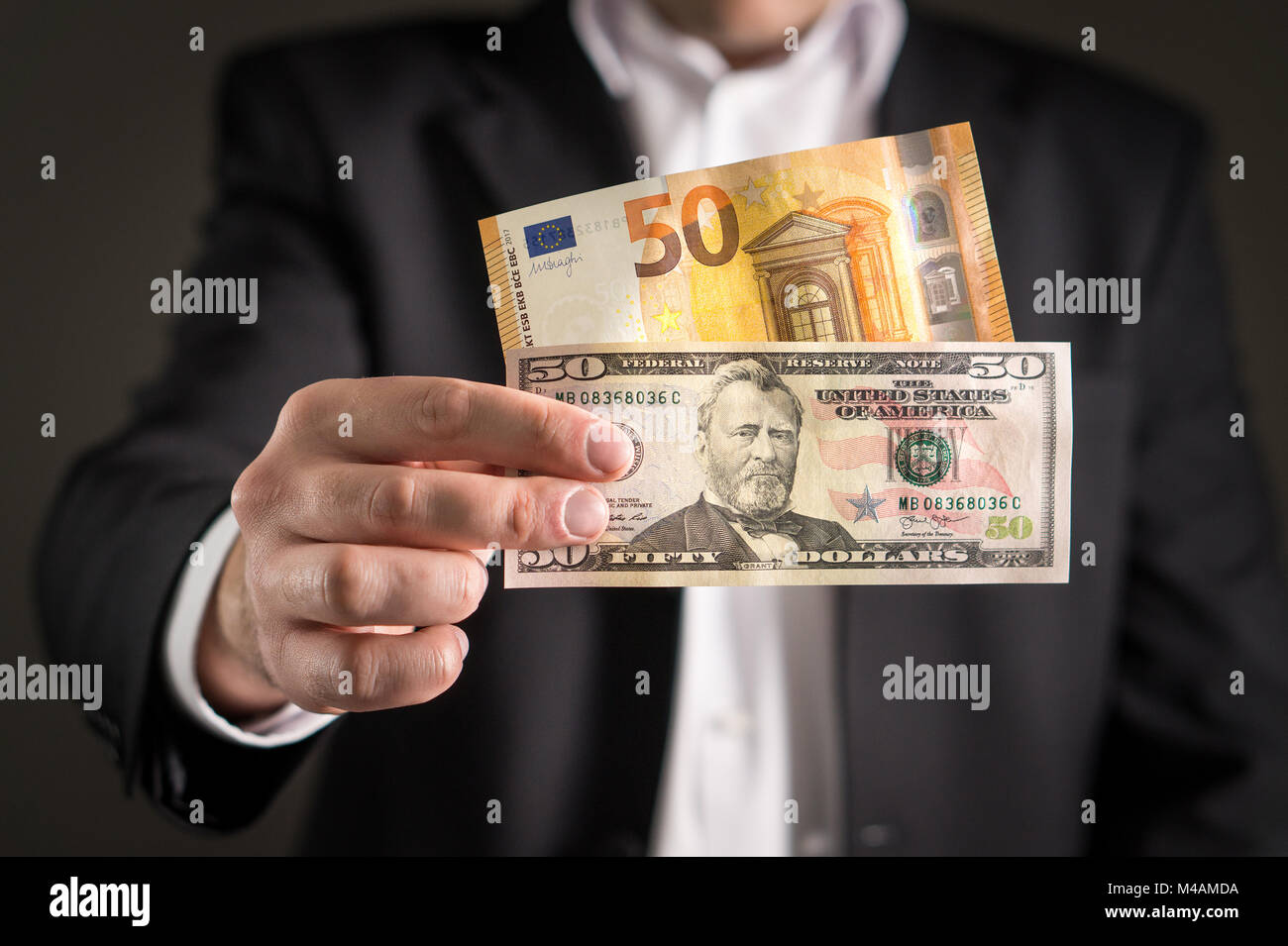 Dollar vs euro. Business man in suit holding 50 banknote and bill in both currency in hand. Exchange rate, world economy and financial concept. Stock Photo