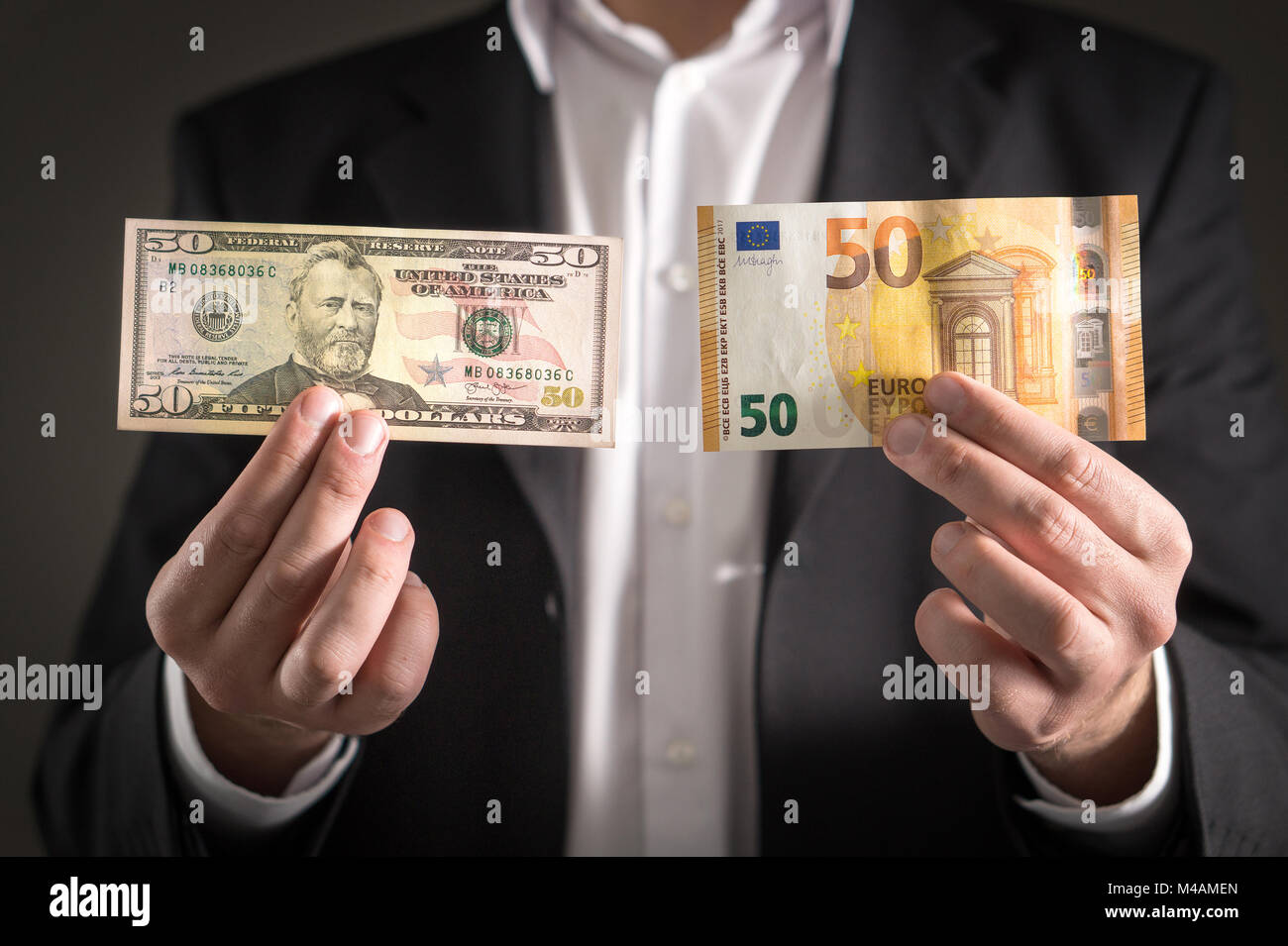 Dollar vs euro. Business man in suit holding 50 banknote and bill in both currency in hand. Exchange rate, world economy and financial concept. Stock Photo