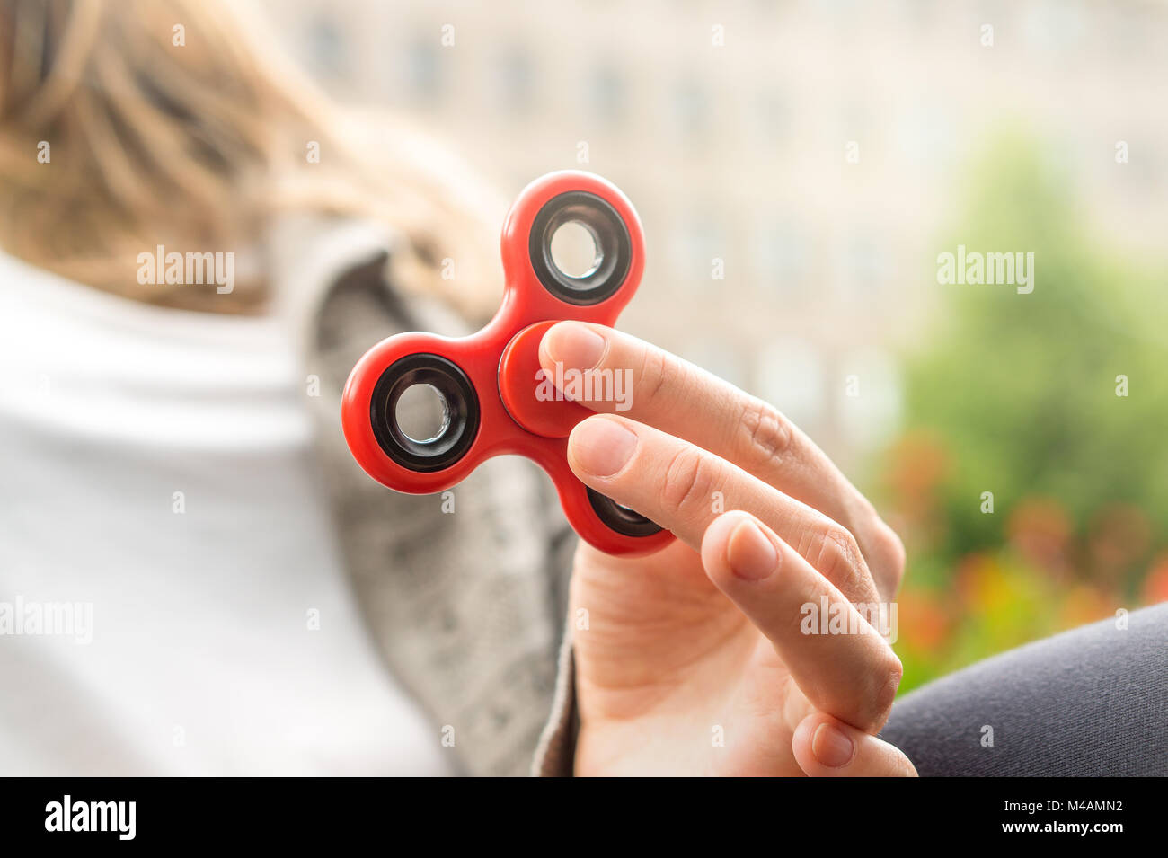 Woman or girl holding red fidget spinner in hand on a sunny summer day. Stock Photo