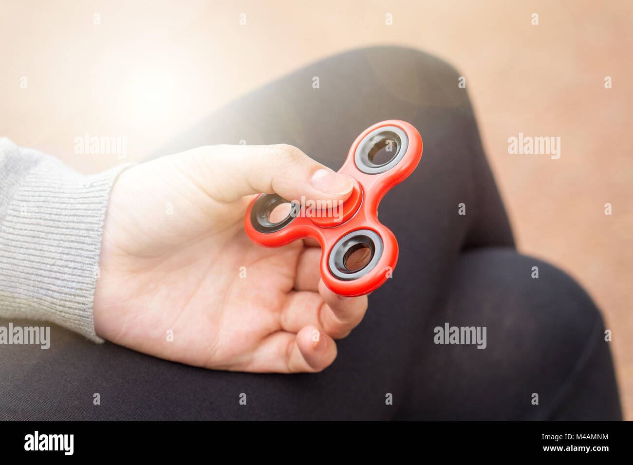 Woman or girl holding red fidget spinner in hand on a sunny summer day. Stock Photo