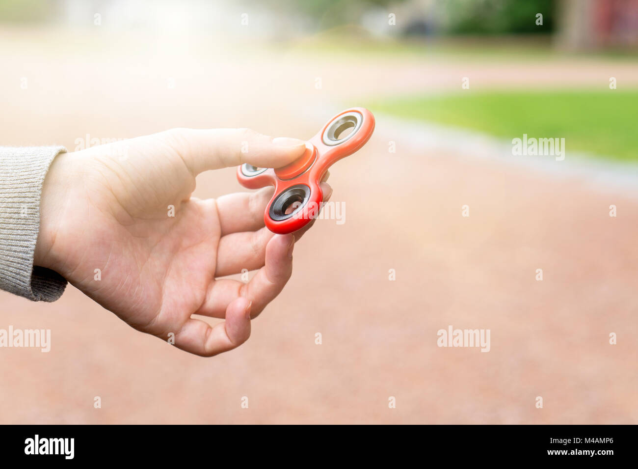 Woman or girl holding red fidget spinner in hand on a sunny summer day in a park outside. Stock Photo