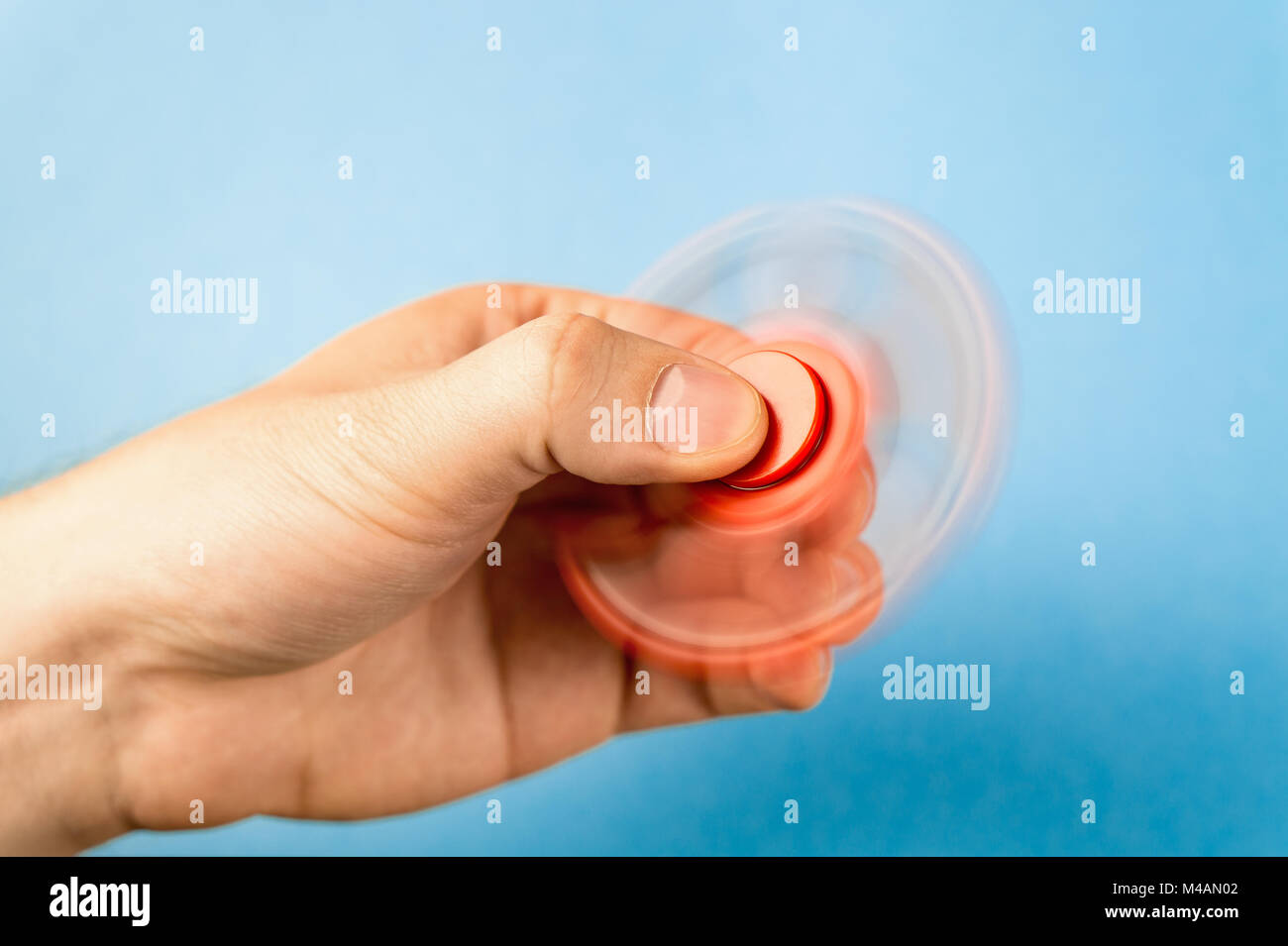 Fidget spinner spinning in hand with blue background. Stock Photo