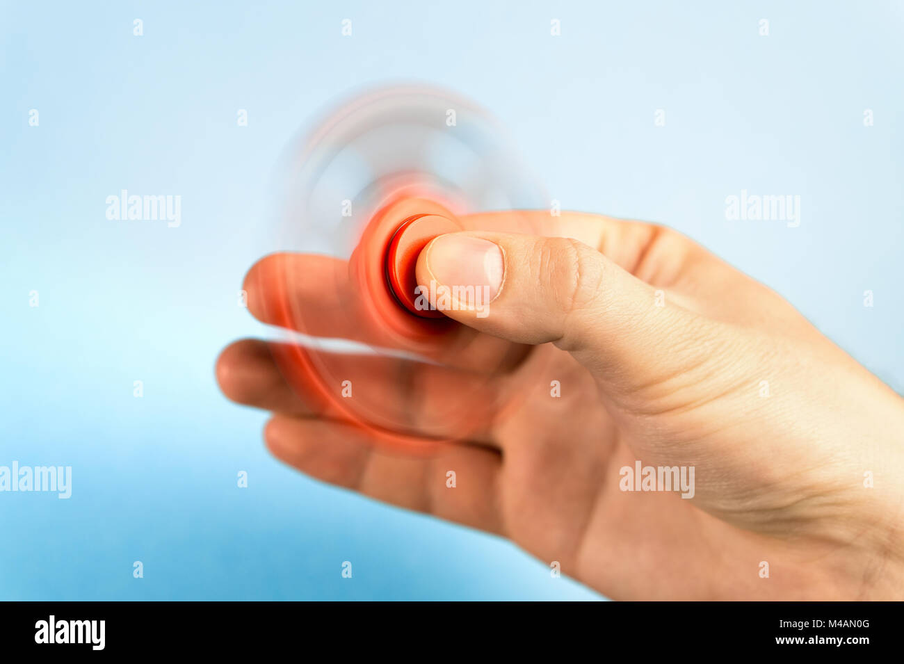 Fidget spinner spinning in hand with blue background Stock Photo