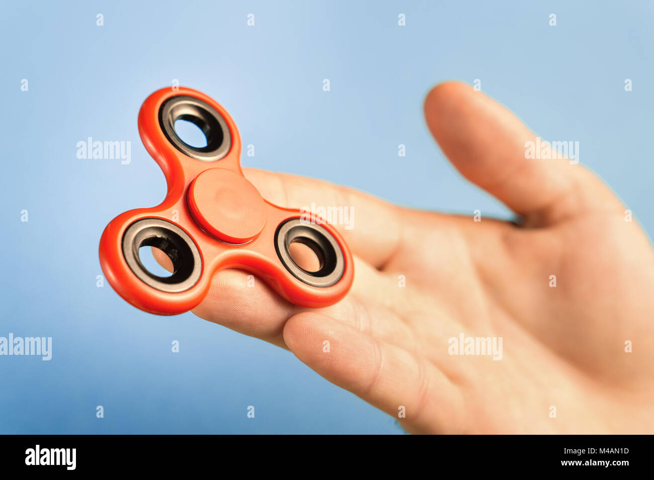 Fidget spinner on hand with blue background. Stock Photo