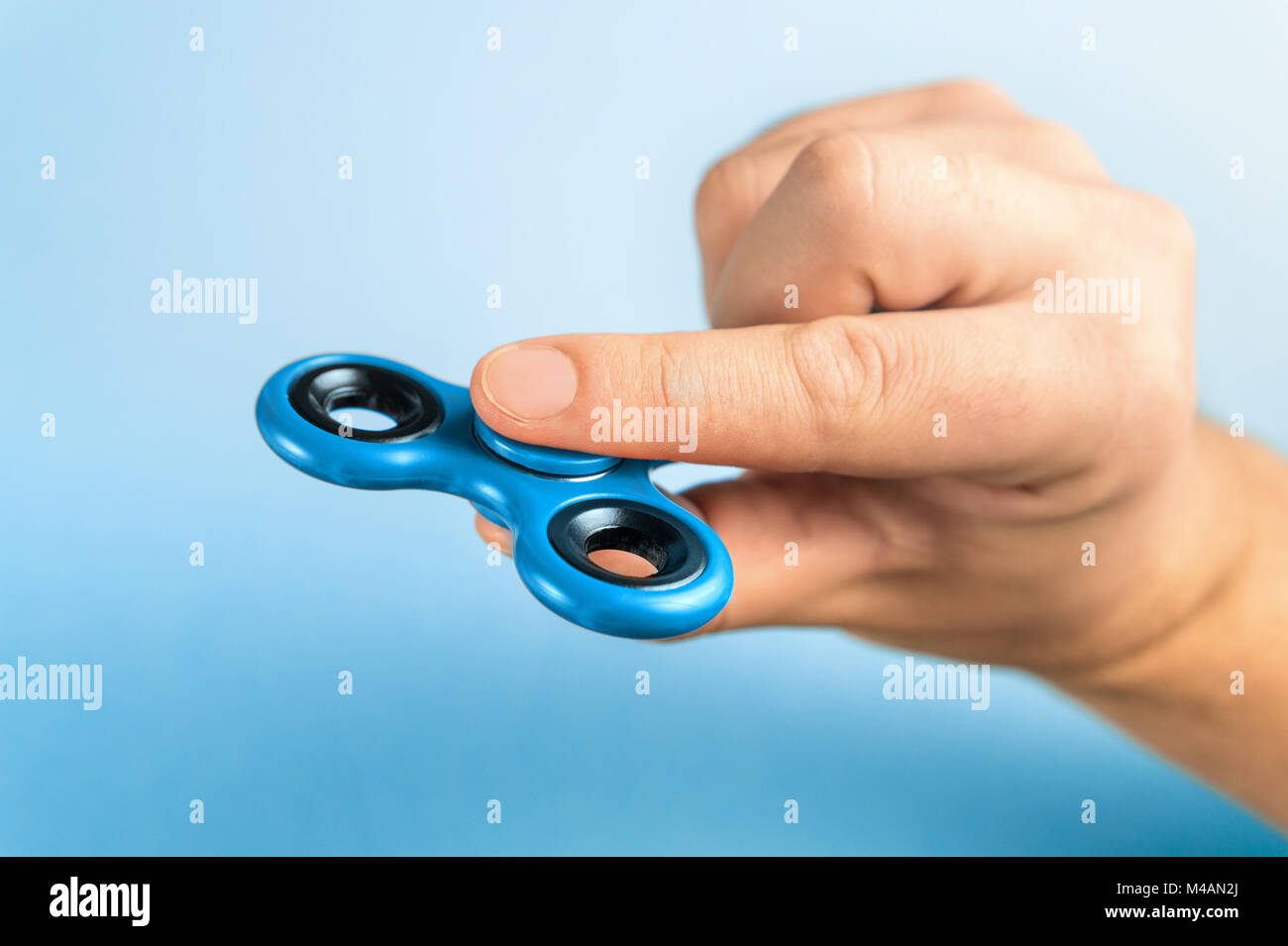 Blue fidget spinner between fingers Stock Photo