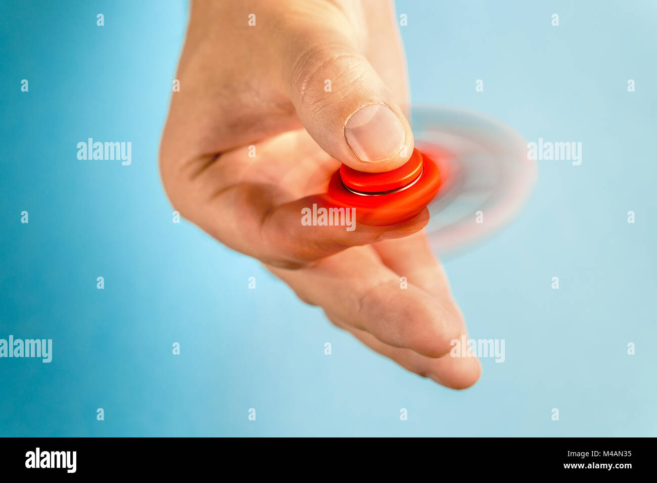 Fidget spinner spinning in hand with blue background. Towards camera. Stock Photo