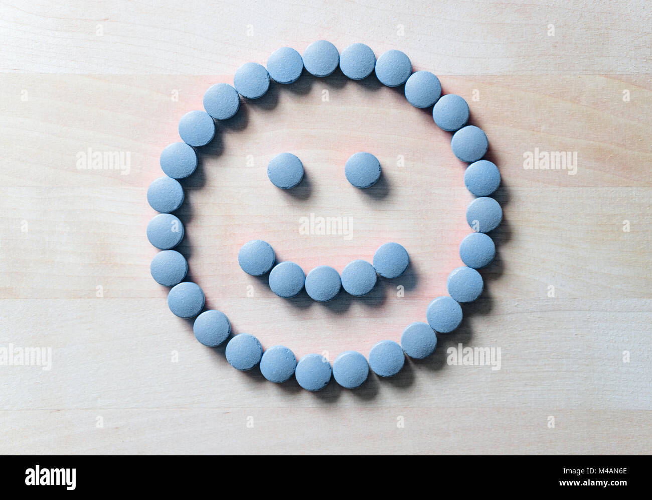 Smiley face from pills on wooden table. Happy and positive feeling from successful healing process or satisfied with health care and doctor services.  Stock Photo