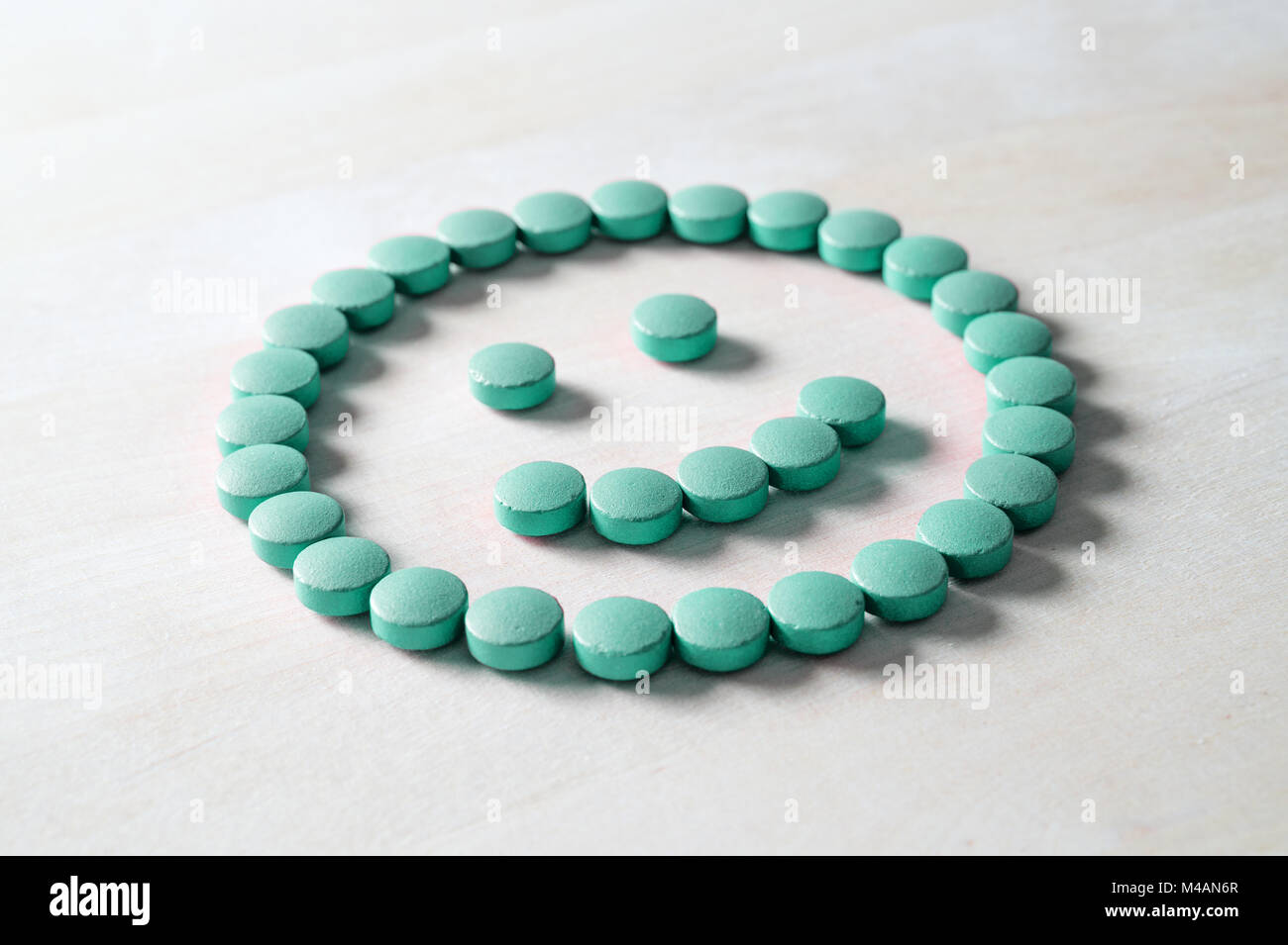 Smiley face from pills on wooden table. Happy and positive feeling from successful healing process or satisfied with health care and doctor services.  Stock Photo