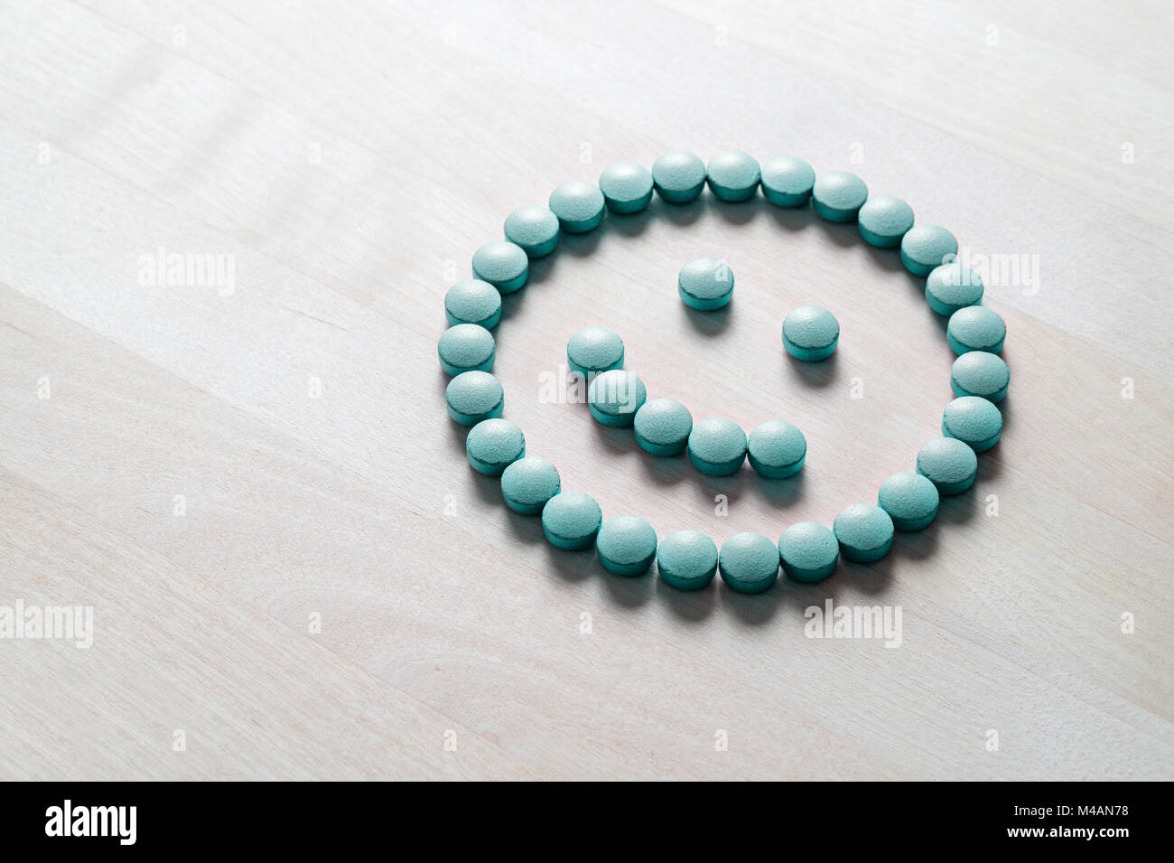Smiley face from pills on wooden table. Happy and positive feeling from successful healing process or satisfied with health care and doctor services.  Stock Photo