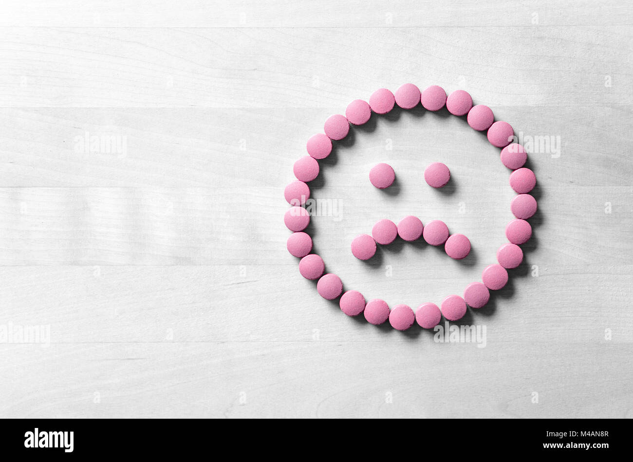 Clinical depression, mental illness and disorder or bad health services concept. Sad smiley face made from pills, medicine and tablets on wooden table Stock Photo