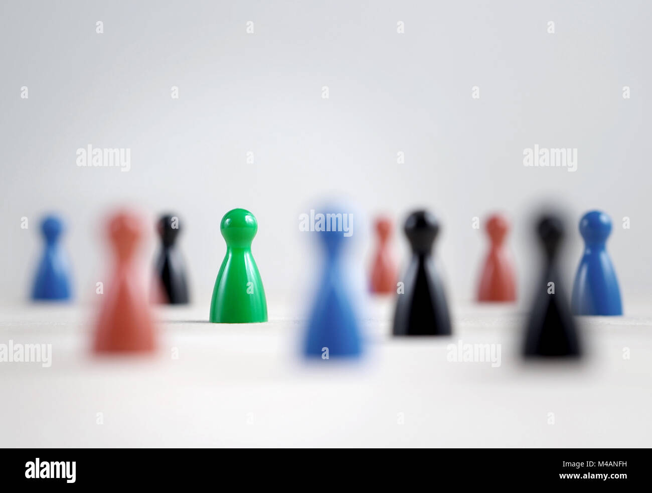 Many board game pawns on table, selective focus on the green one. Being brave, be yourself and originality concept. Diversity and tolerance. Stock Photo