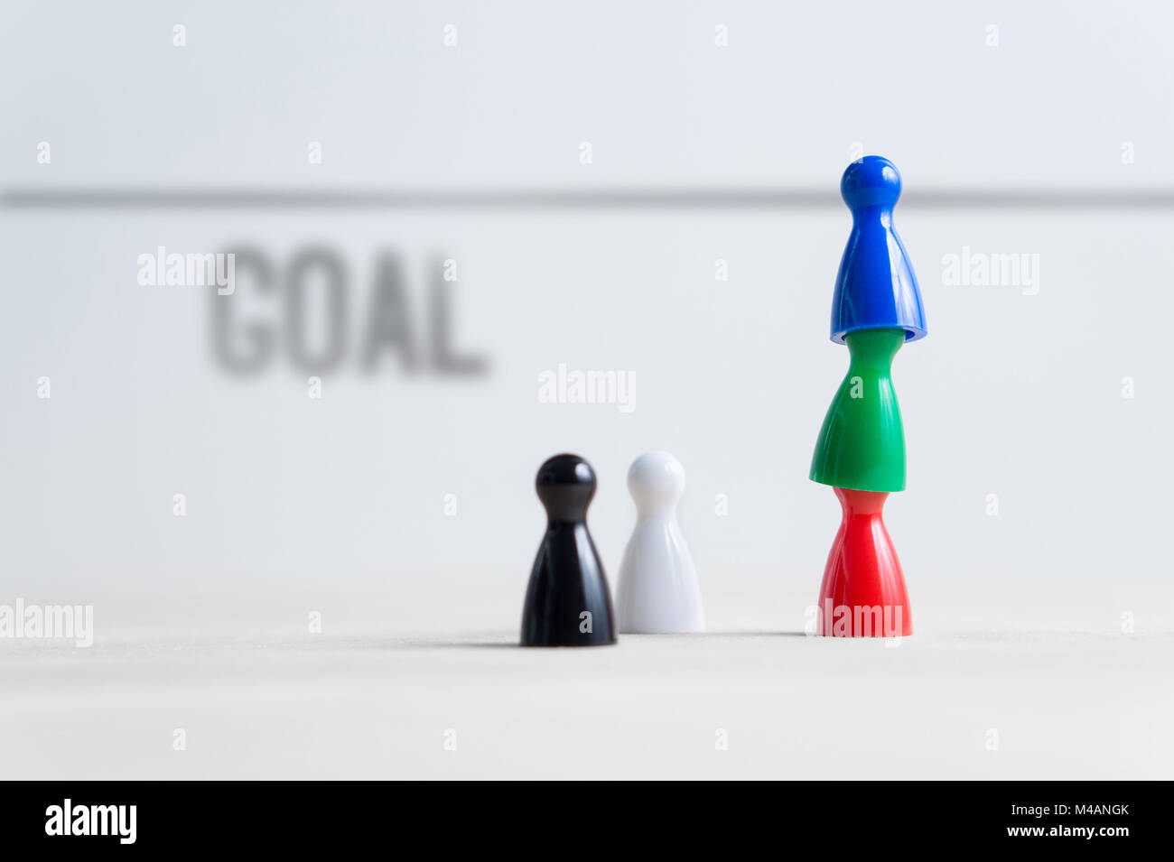 Teamwork, reaching goals, working together and success concept. Colorful board game pawns on each other. Cooperation, leadership and achievement. Stock Photo
