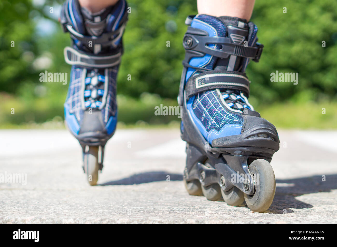 Roller skating in summer. Blue rollerskating on tarmac and asphalt on sunny day. Inline skating on asphalt in the city. Fun free time activity. Stock Photo