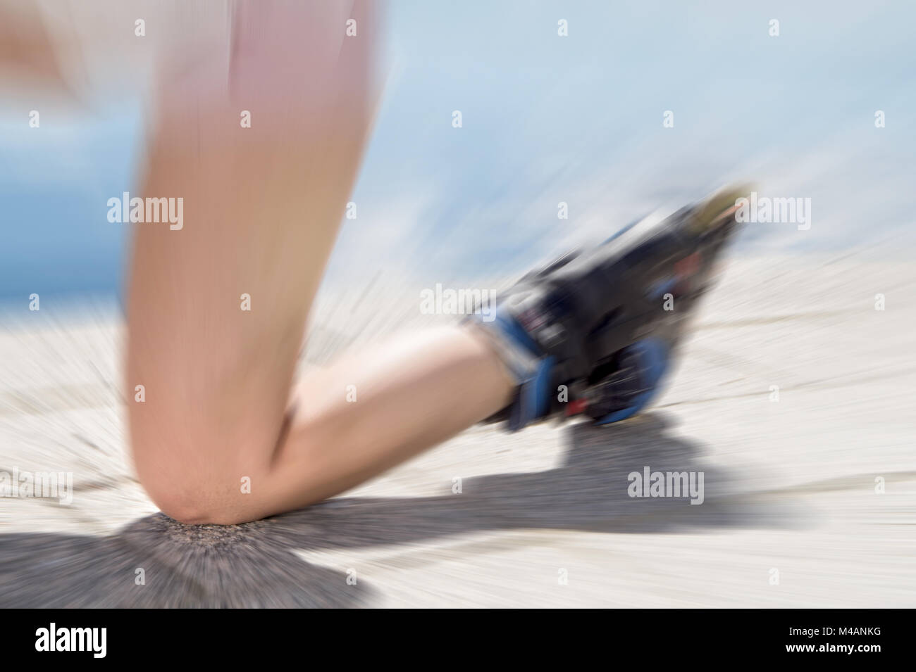 Young woman on roller skates falling down on ground, asphalt and road knee first. Inline and rollerskates accident. Painful injury to leg. Stock Photo