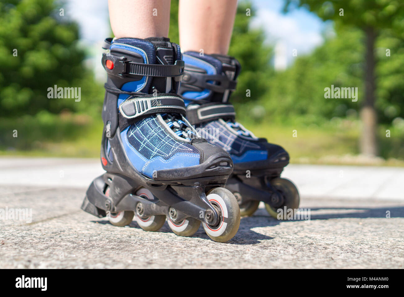Roller skating in summer. Blue rollerskates on tarmac and asphalt on sunny day. Inline skating on asphalt in the city. Fun free time activity. Stock Photo