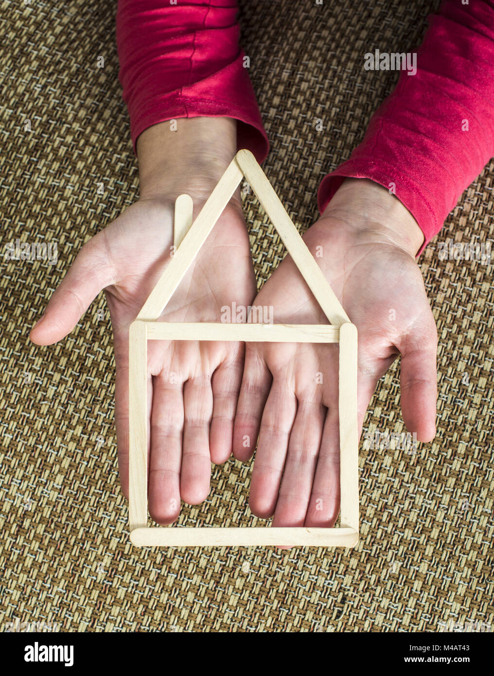 Hands holding model house made of wooden sticks Stock Photo - Alamy