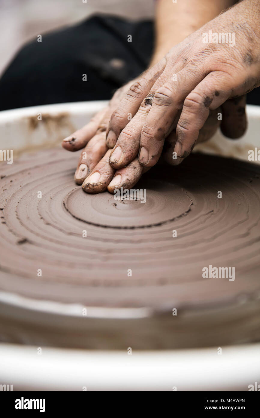 Close up detail view at an artist makes clay pottery on a spin wheel
