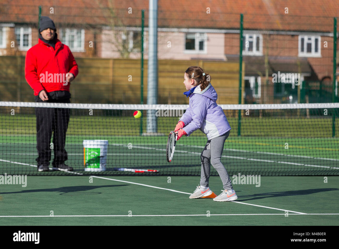 Children's tennis coaching session / lesson taking place on a fullsize tennis court with kids