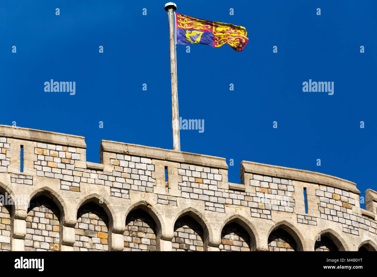 The Royal Standard flag flying on / from a flagpole / pole at Windsor Castle, UK. It is flown at royal residences only when the sovereign is present. Stock Photo